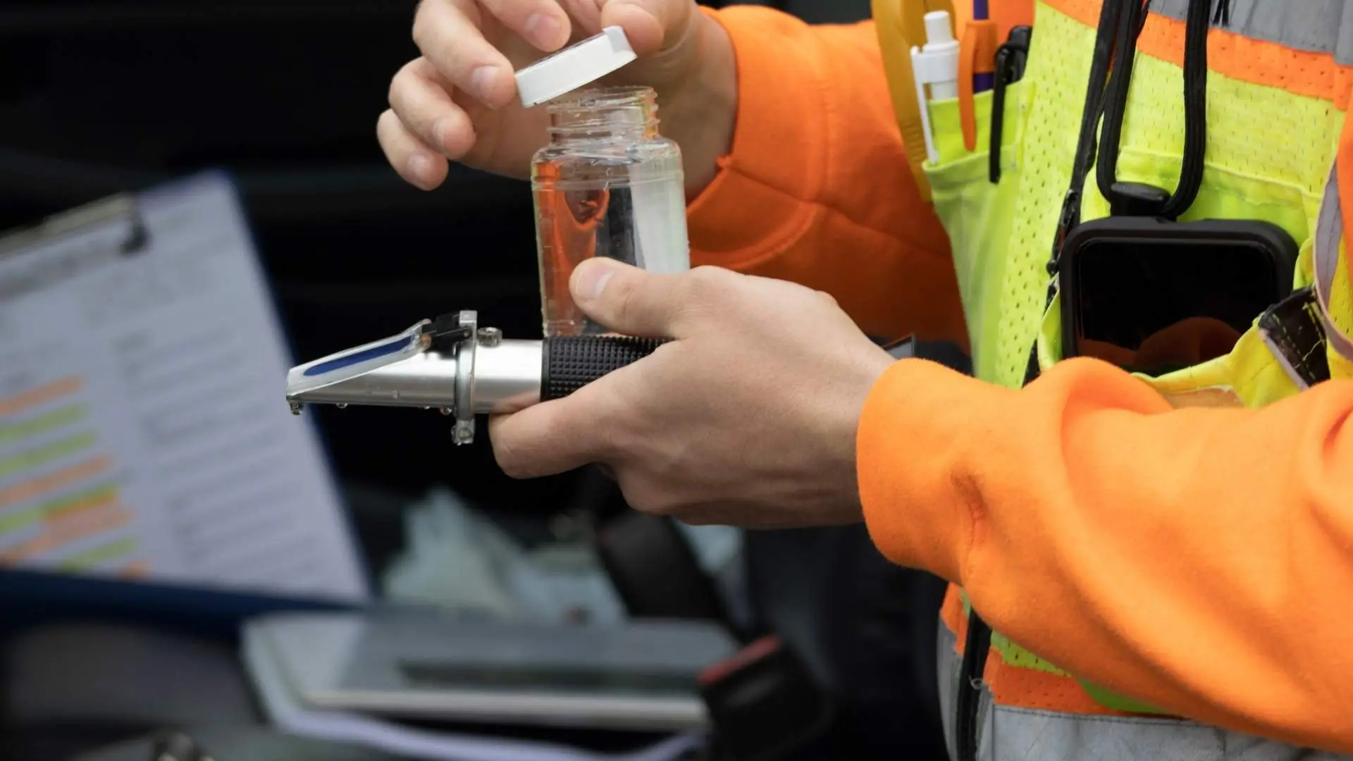 Worker testing liquid with refractometer