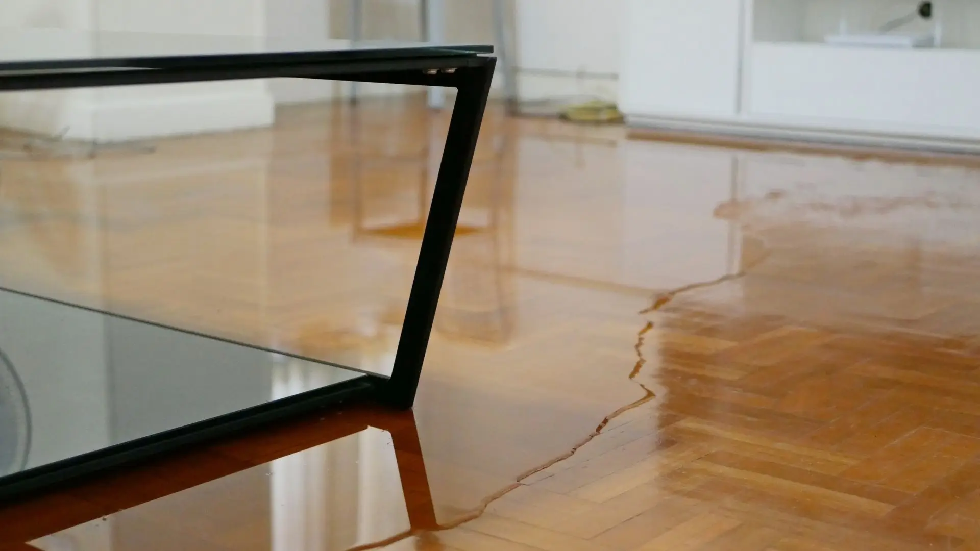 Flooded wooden floor near black table legs.
