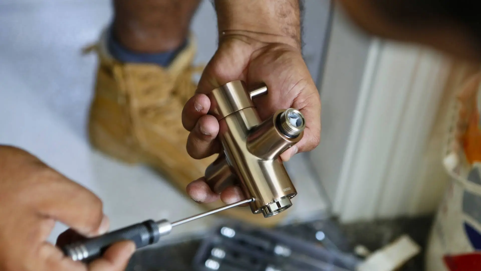 Person assembling brass plumbing fitting with screwdriver